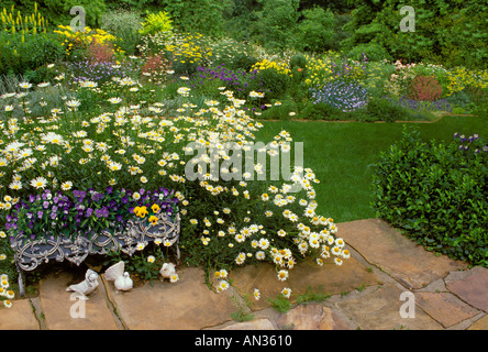 Antike filigrane Pflanzmaschine aus Eisen auf einer Flaggestone-Terrasse von einem großen Blumengarten und einer Ziegelterrasse mit Keramikherden, Missouri USA Stockfoto