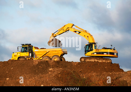 Caterpillar 330c verfolgte Bagger und Glocke b25d artikuliert Muldenkipper bei der Arbeit auf einer Baustelle Boden ausheben Stockfoto