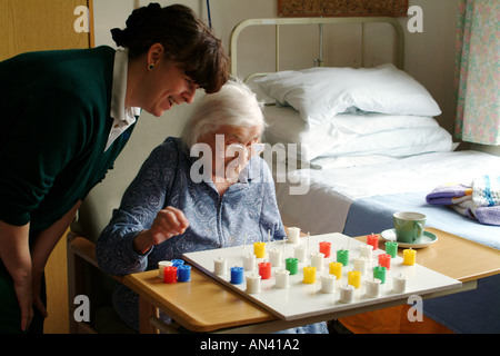 Ältere Frau Patienten spielt Solitaire mit einer Krankenschwester in Spitalabteilung England UK Stockfoto