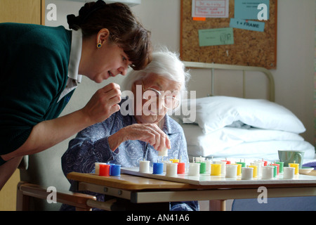 Ältere Frau spielt Solitaire mit einer Krankenschwester im Krankenhaus Ward England UK Stockfoto