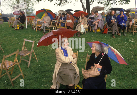 Chelsea Flower Show 1984 Treffpunkt Besuchergruppe wartet auf Freunde. Zwei Frauen sitzen unter ihren Schirmen und plaudern in Großbritannien der 1980er Jahre HOMER SYKES Stockfoto