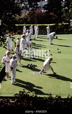 Männer und Frauen, die beim Lawn Bowls-Spiel im Gange sind, auf einem Bowlinggrün in kühlem weiß gekleidetem Blick von oben im sonnigen Guildford Surrey England, Großbritannien Stockfoto