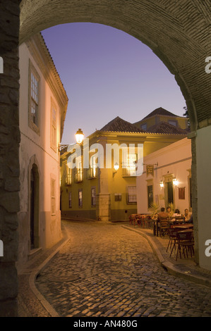 Portugal, Algarve, Faro, Torbogen und einen schmalen gepflasterten Straße in der alten Stadt bei Dämmerung Stockfoto