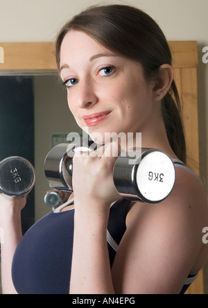 Lächelnde junge Frau mit kleinen Satz von Gewichten im Fitnessstudio Stockfoto