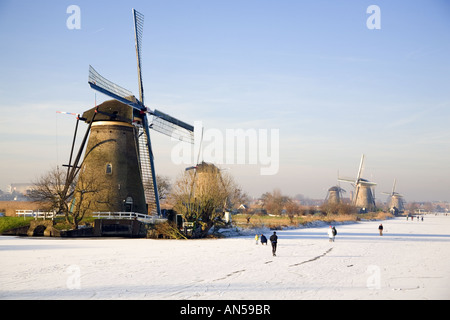 Skater auf dem Schnee bedeckt Kanal nahe den Windmühlen von Kinderdijk, Süd-Holland, Niederlande Stockfoto