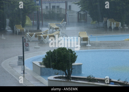 Sehr schwere Regen fällt auf den Pool in einem Hotel in Menorca während einer Sommerdusche Stockfoto