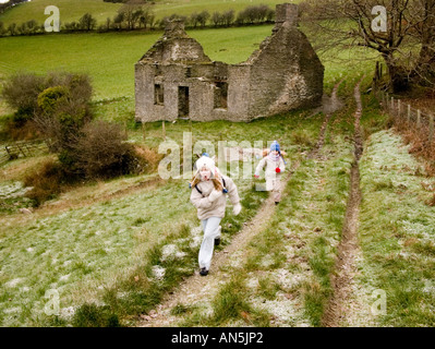 Zwei junge Mädchen, für einen Winter Fuß in die Landschaft von einem alten verlassenen Bauernhaus, Wanderungen Ceredigion Wales UK Stockfoto