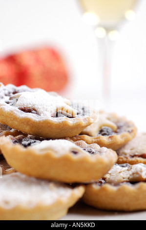 Teller mit Mince Pies bestäubt mit Puderzucker mit Christmas Cracker und Glas Sherry im Hintergrund Stockfoto