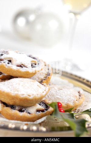 Teller mit Mince Pies dekoriert mit Zweig der Stechpalme und mit Glas Sherry und Weihnachten Kugeln im Hintergrund Stockfoto