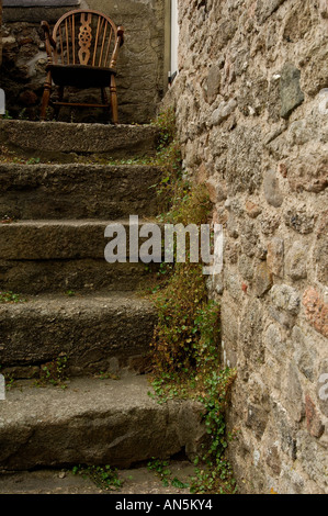 Traditionellen steinernen Stufen an der Seite eines Gebäudes auf Dartmooor mit einem alten hölzernen Stuhl an der Spitze Stockfoto