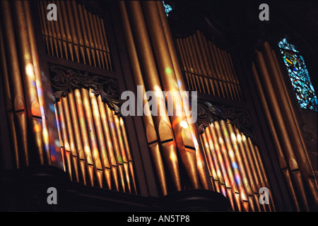 Farben von den Glasfenstern in Birmingham Kathedrale fallen auf die Orgelpfeifen als Sonne durchscheint. Stockfoto