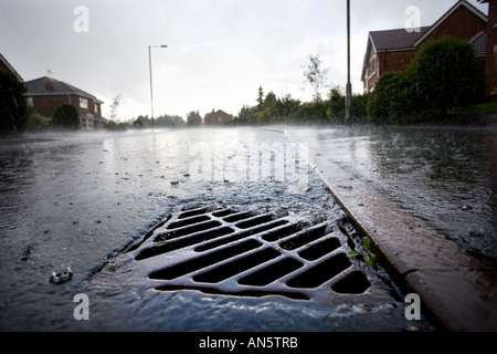 Regenwasser fließt in einen Abfluss an der Seite einer Straße in Redditch, Worcestershire UK während einem Sommergewitter Stockfoto
