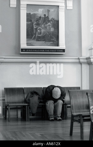 Obdachloser in einer Kirche unter ein Bild von Christus Stockfoto