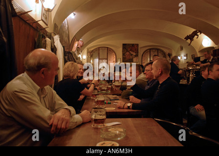 Menschen, die in U Zlateho Tygra pivnice 'Tiger Beer Cellar' in Stare Mesto, Altstadt Prag, Tschechische Republik, Bier trinken und mit Bierkrügen toasten Stockfoto