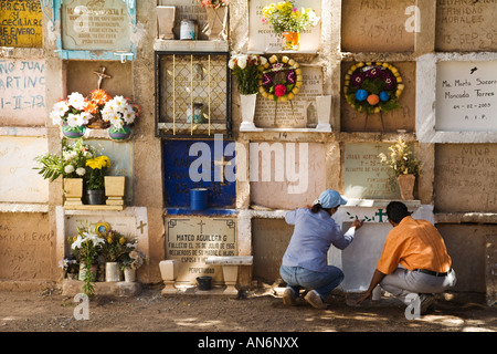 Mexiko-Guanajuato-Mann und Frau malen Krypta im Friedhof Tag der toten Feier Zeilen der Krypten Blumen auf Sims Stockfoto