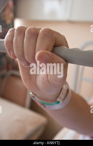 Weibliche hand mit Namensschild an Handgelenk holding Haltegriff über Krankenhausbett Stockfoto