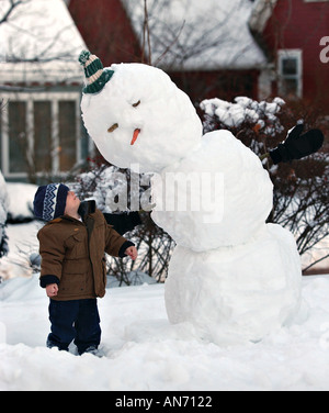 Kleiner Junge neben einem Schnee Mann Stockfoto