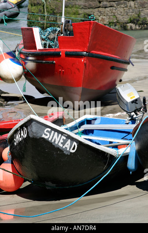 Eine alte Stil Fischerei Currach namens Sinead und einem größeren roten Boot, das beide gestrandet, auf dem sandigen Boden Stockfoto
