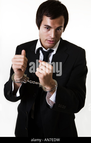 Professionellen jungen Geschäftsmann im Business-Anzug mit den Händen in Handschellen mit weißen Kragen Kriminalität Stockfoto