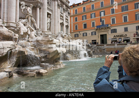 Ein weiblicher Touristen hält ihre Kamera zu erfassen, dass ein Bild von Pietro da Cortona Bernini Nicola Salvi entworfen, Trevi-Brunnen Stockfoto