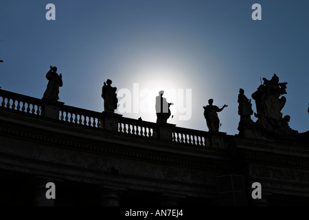 Fünf von den Statuen von Heiligen, die das Quadrat hoch oben auf dem Dach Kreisen Linie der letzten Nachmittag Sonne leuchtet hinter St Peters Stockfoto