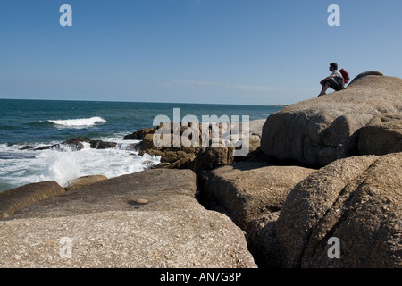 Männliche Figur saß auf felsigen Strand Stockfoto