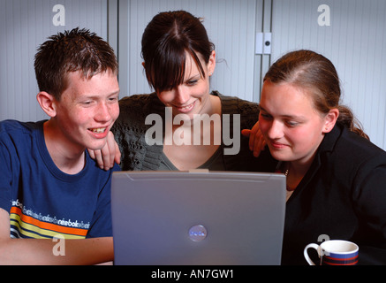 EIN TEENAGER-MÄDCHEN UND JUNGEN ARBEITEN AUF EINEM LAPTOPCOMPUTER UNTER ANLEITUNG VON EINEM LEHRER UK Stockfoto