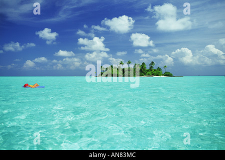 Entspannen Sie in einem Traumurlaub auf Luftmatratze unter blauem Himmel voller Wattebällchen in der Nähe von kleinen einsamen Insel im Paradies Stockfoto