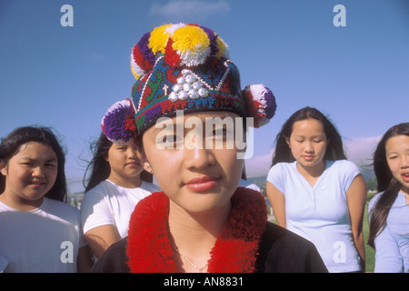 13 jährige Asiatin in 'native Kleider' vor einer Gruppe von asiatischen Mädchen in westliche Kleidung Stockfoto