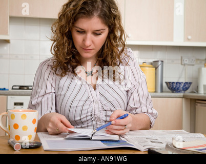 junge weibliche Frau oder Student zu Hause überprüfen klassifizierte Anzeigen und auf der Suche nach einem Job oder Unterkunft Tagebuch Stockfoto