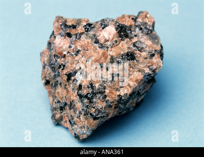 ein Exemplar aus rosa Granit auf blauem Hintergrund Stockfoto