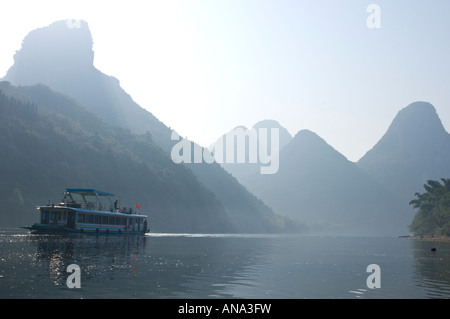 China-Guangxi Yuangshuo Touristenboot Kreuzfahrt auf dem Li-Fluss im Morgenlicht mit typischen Kalksteinspitzen in bkgd Stockfoto