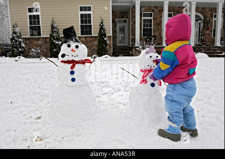 Kinder bauen Schneemann mit Mutter nach einem Winter Schneefall Stockfoto