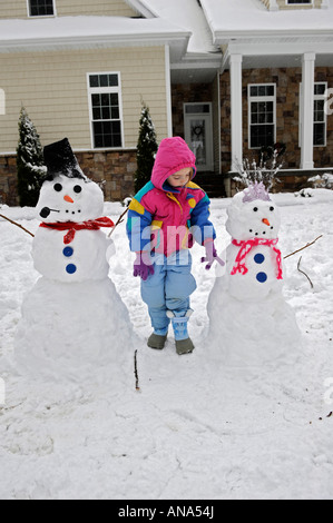 Kinder bauen Schneemann mit Mutter nach einem Winter Schneefall Stockfoto