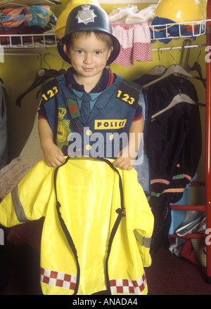 Kleiner Junge im Vorschulalter in Polizeikleidung, der mit Kleidung spielt, Großbritannien Stockfoto