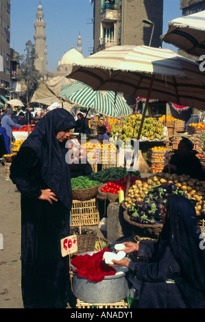 Ägypten Kairo offenen Markt in der Nähe von der Citadelle Ansicht mit Frau kaufen Käse aus einem Stall und Moschee und Obst Stände in bkgd Stockfoto