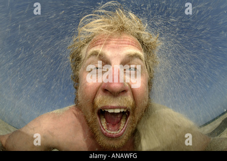 verrückter junge Mann schütteln Sand aus seinem Haar Stockfoto