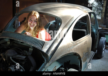 Lächelnde Blondine in der Schale der eine abgespeckte VW Käfer Stockfoto