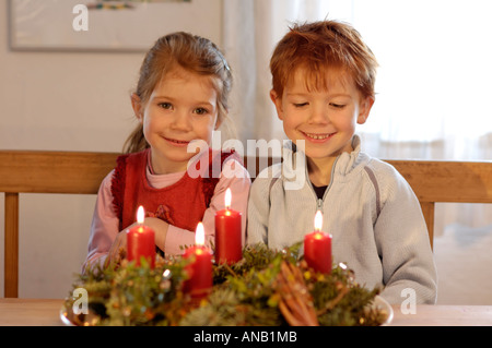 Kinder in der Weihnachtszeit mit Kerzen und Adventskranz Stockfoto