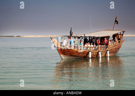 Seitenansicht eines traditionellen hölzernen Dhow flott mit einer Gruppe von Touristen an Bord, auf eine Kreuzfahrt, Abu Dhabi, VAE Stockfoto