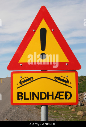 Eine typische Straßenschild in Island Warnung vor einem blinden Gipfel und zeigt auch Schnee Markierungen auf der Straße Stockfoto