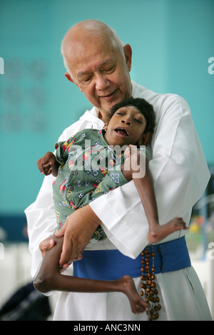 Vater Richard Ho Lung, Gründer und Leiter der römischen Katholischen Congrigation "Missionare der Armen" mit behinderten Kind Stockfoto