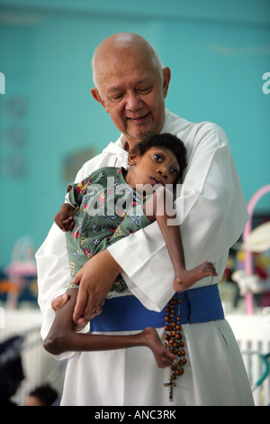 Vater Richard Ho Lung, Gründer und Leiter der römischen Katholischen Congrigation "Missionare der Armen" mit behinderten Kind Stockfoto