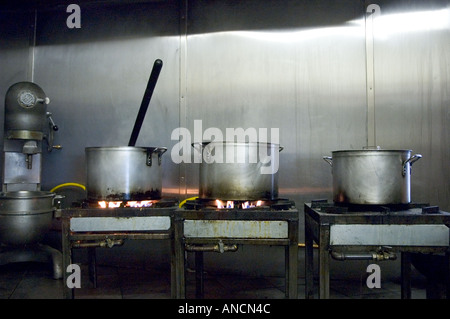 Drei Edelstahl-Töpfe auf dem Herd in der Küche eines Restaurants. Stockfoto