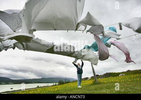 Frau Aufhängen von Wäsche in den Wind auf der Kleidung Linie Egilsstadir Island Stockfoto