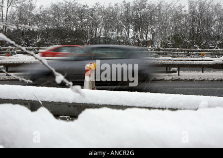 Autos vorbei Schneeverwehungen neben behandelten gesalzene Autobahn beschleunigen Stockfoto