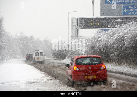 Van und Autos befahren behandelten Straße neben Autobahn Zeichen im Schneesturm Stockfoto