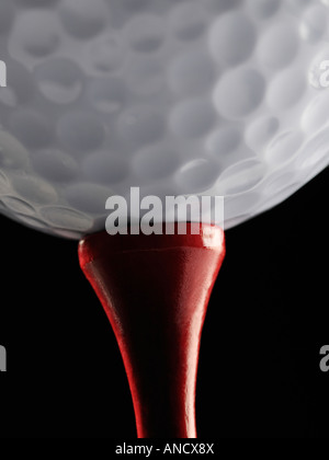 Golfball und Tee schließen gegen einen schwarzen Hintergrund Stockfoto