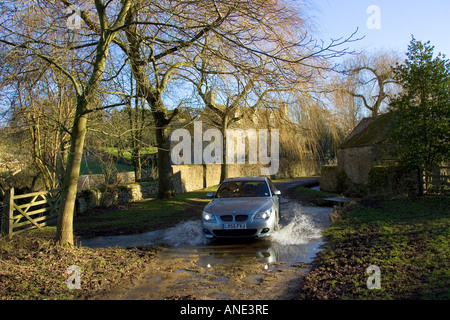 BMW 5er Auto fährt durch Land Lane Ford Swinbrook Oxfordshire Vereinigtes Königreich Stockfoto