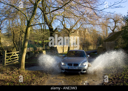BMW 5er Auto fährt durch Land Lane Ford Swinbrook Oxfordshire Vereinigtes Königreich Stockfoto